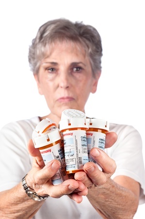 A woman holding several bottles of prescription drugs